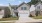 a house with a driveway and a tree and signs in the yard